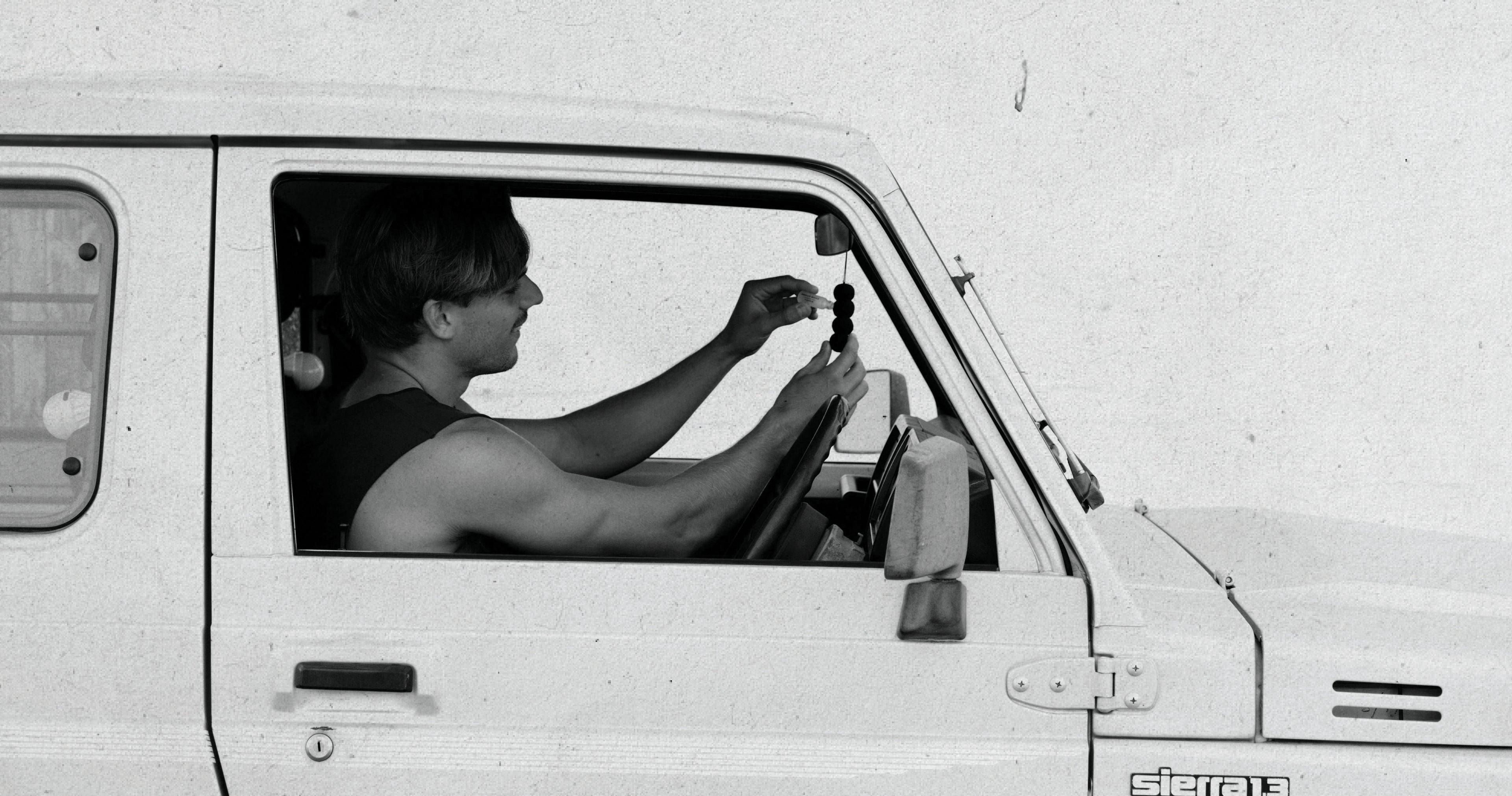 Male sat in car using reusable air freshener in his car 